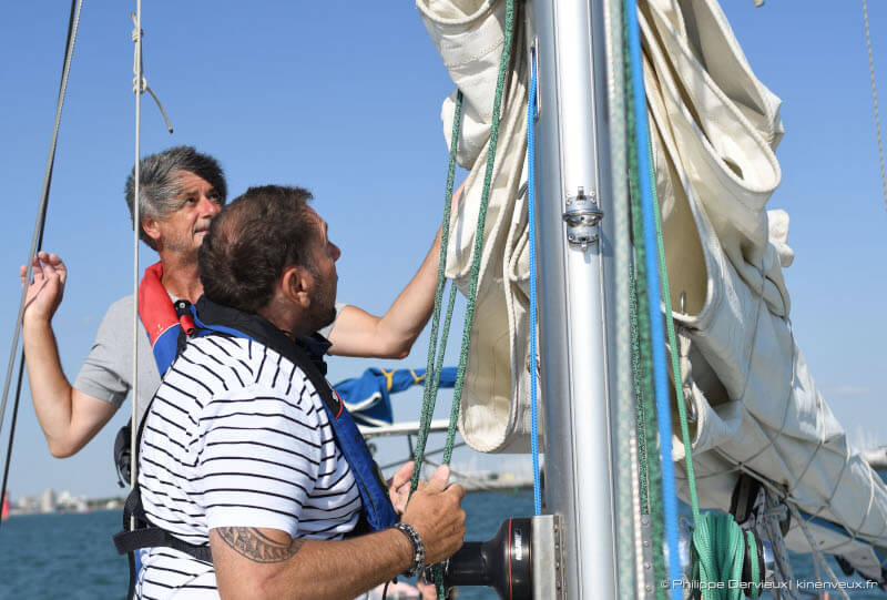 un client qui hisse la grand voile à bord de kelone